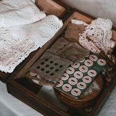 Wooden box holding folded white lace trims and spools of thread