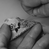 Hands stitching a small piece of embroidered lace
